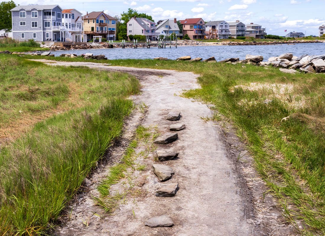 Warwick, RI - Coastal Gravel Road With a Small Seaside Neighborhood in the Background in East Greenwich, Rhode Island